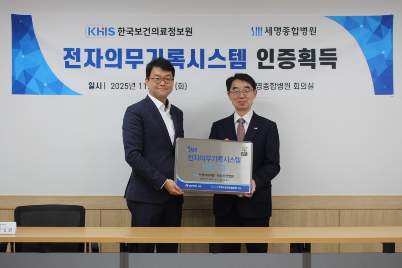 사진에는 회의실 공간에서 한국보건의료정보원과 세명종합병원 관계자 2명이
‘EMR 전자의무기록시스템 인증 기관’ 인증패를 함께 들고 기념 촬영을 하고 있는 모습이 담겨 있다.

중앙의 인증패에는
‘EMR 전자의무기록시스템 인증 기관’이라는 문구와 함께
세명종합병원 명칭이 표기되어 있으며,
해당 기관이 공식적으로 EMR 인증을 획득했음을 나타낸다.

배경 현수막에는
‘전자 의무기록 시스템 인증 획득’이라는 제목과 함께
한국보건의료정보원(KHIS)과 세명종합병원 로고,
인증 행사 일시 및 장소 정보가 표시되어 있다.
